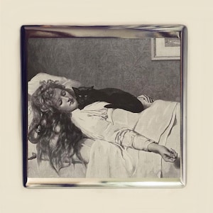 May include: A black and white photograph of a woman sleeping in a bed with a black cat curled up on her chest.