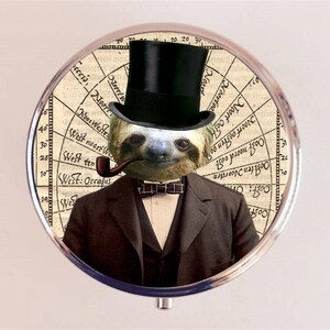 May include: A round, silver-colored compact mirror with a vintage-style design. The lid features a sloth wearing a top hat and a bow tie, holding a pipe in its mouth. The background is a compass with numbers and text.