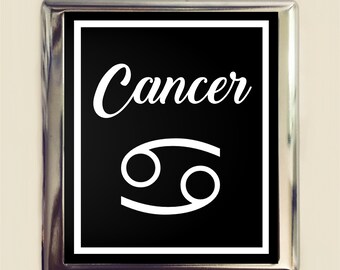 May include: A black and white metal sign with a silver frame. The sign features the word "Cancer" in white cursive lettering and the Cancer zodiac symbol in white.
