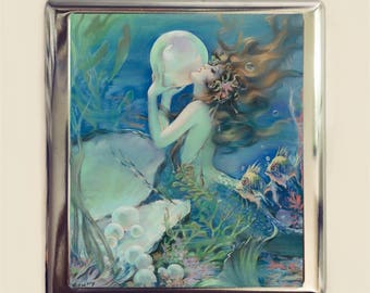 May include: A vintage illustration of a mermaid holding a large pearl in an underwater scene. The mermaid has long flowing hair and is surrounded by seaweed and fish. The pearl is iridescent and has a soft glow. The background is a deep blue with hints of green and purple.