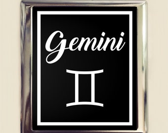 May include: A silver metal sign with a black background and white text. The sign says "Gemini" and features the Gemini astrological symbol.