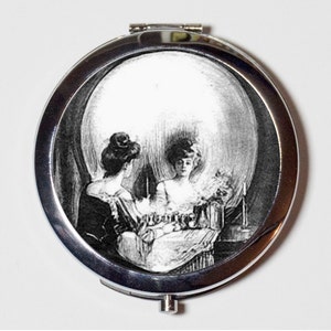 May include: A silver compact mirror with a black and white image of a skull superimposed over two women sitting at a table. The image is a classic optical illusion.