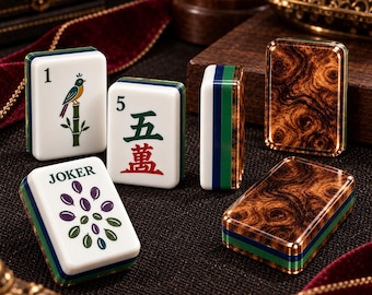 May include: A set of rectangular Mahjong tiles featuring white faces with colorful illustrations, including a bird on a bamboo stalk, the number 5 with Chinese characters, and a Joker tile with purple and green oval shapes, plus wood-grain backs.