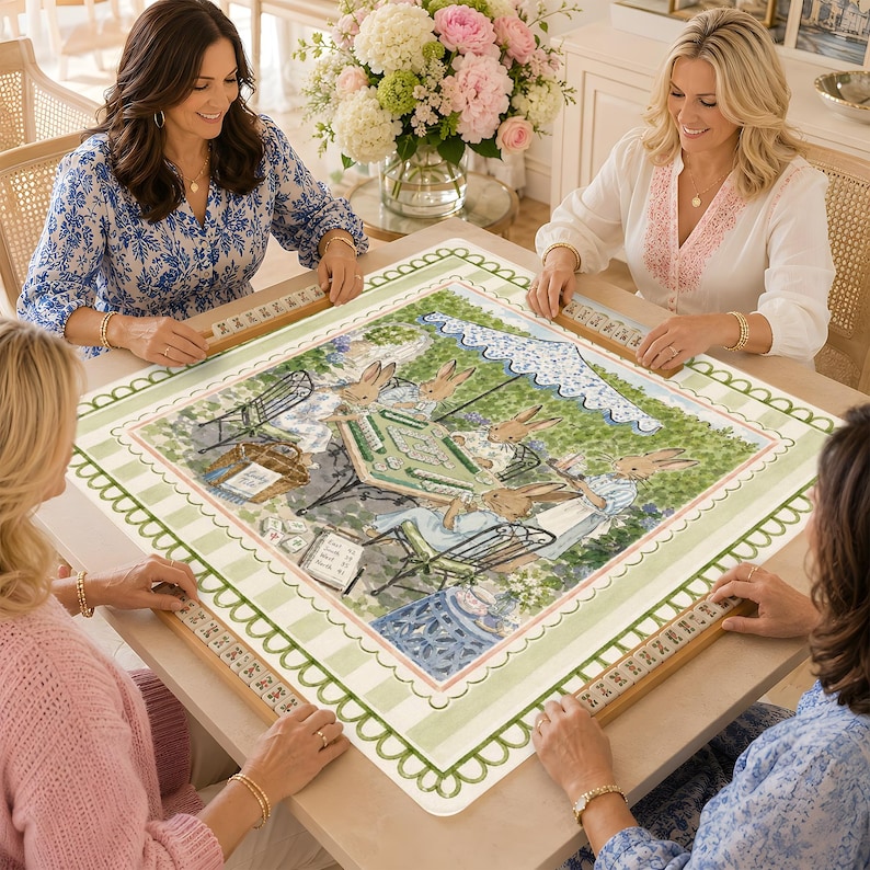 May include: A square mahjong table cover featuring a central illustration of rabbits playing a game outdoors under a blue and white scalloped umbrella. The border has a light green and white striped pattern with a scalloped edge design.