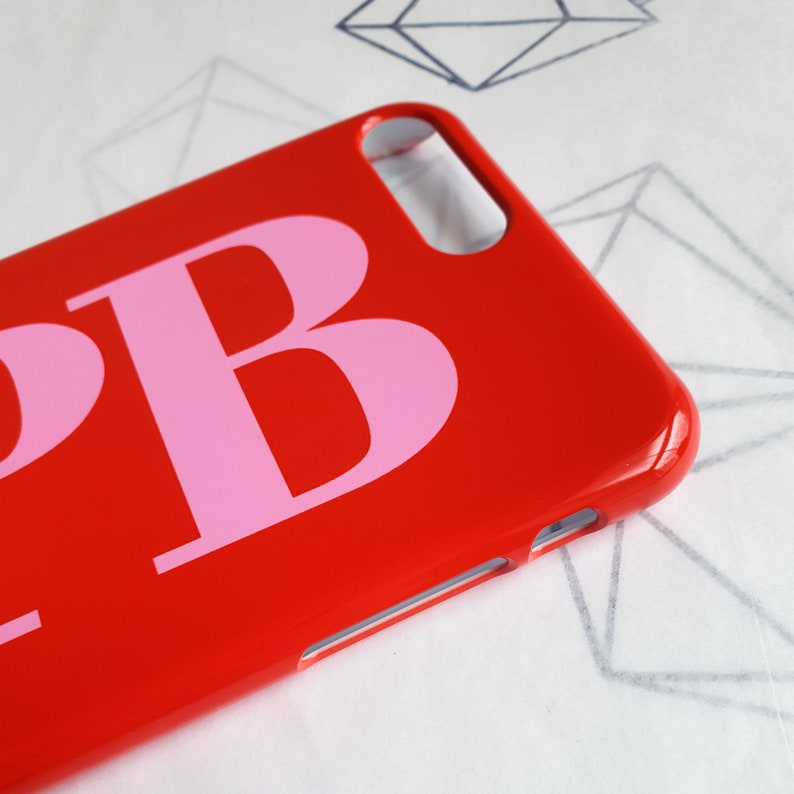 May include: A red phone case with a pink letter "B" printed on it.