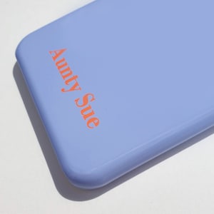 May include: A light blue phone case with the text "Aunty Sue" printed in orange.