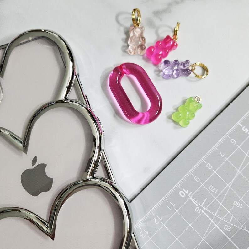 Op de afbeelding: Een set van vijf kleurrijke gummy bear bedels, waaronder roze, paars, groen en helder. De bedels zijn bevestigd aan gouden springringen en zijn perfect om een speelse touch toe te voegen aan sieraden of sleutelhangers.