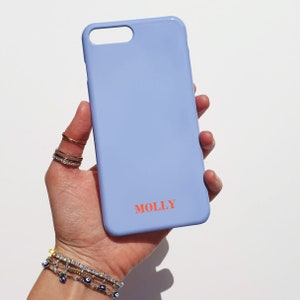 May include: A light blue phone case with the name "MOLLY" printed in orange letters.
