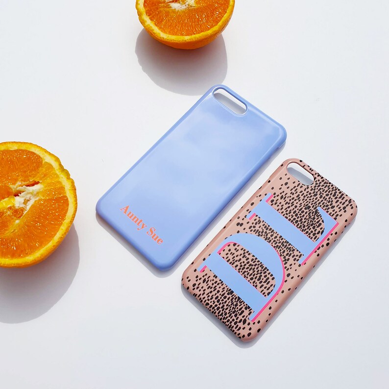 May include: Two phone cases, one light blue with the text "Aunty Sue" and one pink with a black and white spotted pattern and the letter "D" in blue.