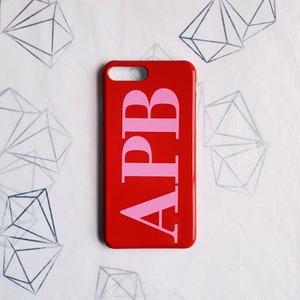 May include: Red phone case with the letters "APB" in pink.