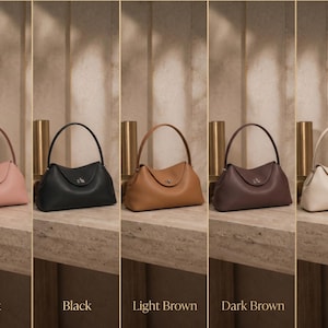 May include: Five structured handbags with a single top handle and a central metal turn-lock closure. The bags are displayed in a row in colors labeled as pink, black, light brown, dark brown, and milk, each featuring a smooth, curved silhouette.