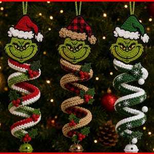 May include: Three crocheted spiral ornaments featuring green character faces wearing Santa hats. The first has red and white stripes, the second has tan and red plaid, and the third has green and white snowflake patterns, each with a metal bell.
