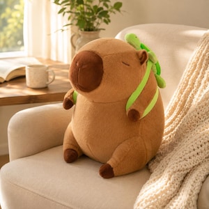 May include: A plush capybara toy with brown fur, a dark brown snout, and closed eyes. The capybara wears a bright lime green backpack with a small, light green turtle plush attached to the top, featuring dark brown feet and a rounded body shape.