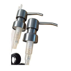 May include: Two silver soap dispensers with clear plastic tubes and black rubber rings. The dispensers have a silver lever on the top.