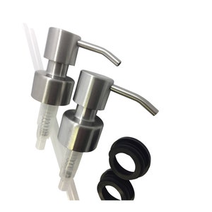 May include: Two silver soap dispensers with clear tubes and black rubber rings. The dispensers have a pump mechanism and a spout.