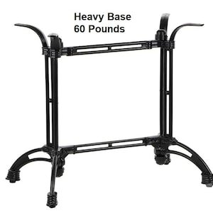May include: Black metal table base with curved legs and a rectangular frame. The text "Heavy Base 60 Pounds" is visible at the top. The base is designed to support a tabletop.