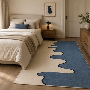 K&ouml;nnte beinhalten: Ein rechteckiger Teppich mit einem zweifarbigen Design, bestehend aus einem cremefarbenen Bereich und einem gro&szlig;en blauen Bereich, die durch eine kr&auml;ftige, schwarze, wellenf&ouml;rmige Linie getrennt sind, die ein flie&szlig;endes, abstraktes Muster bildet.