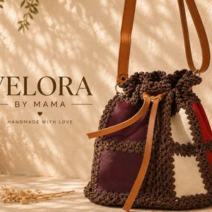 May include: A bucket bag featuring a patchwork design of dark red, maroon, and white fabric panels joined by dark brown crocheted borders. The bag includes a tan leather drawstring closure and a matching tan leather shoulder strap. Text reads VELORA BY MAMA HANDMADE WITH LOVE.