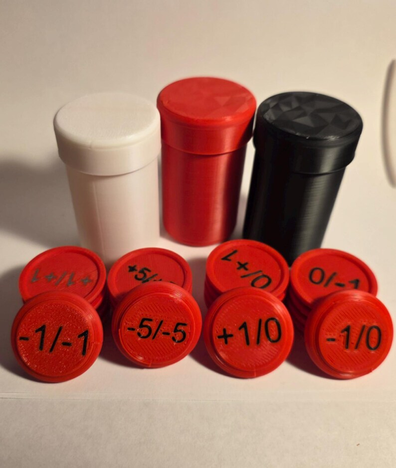 May include: Three cylindrical containers in white, red, and black, accompanied by a collection of red circular tokens. Each token features black printed numerical values including -1/-1, -5/-5, +1/0, 0/-1, and +1/+1, designed for game tracking.