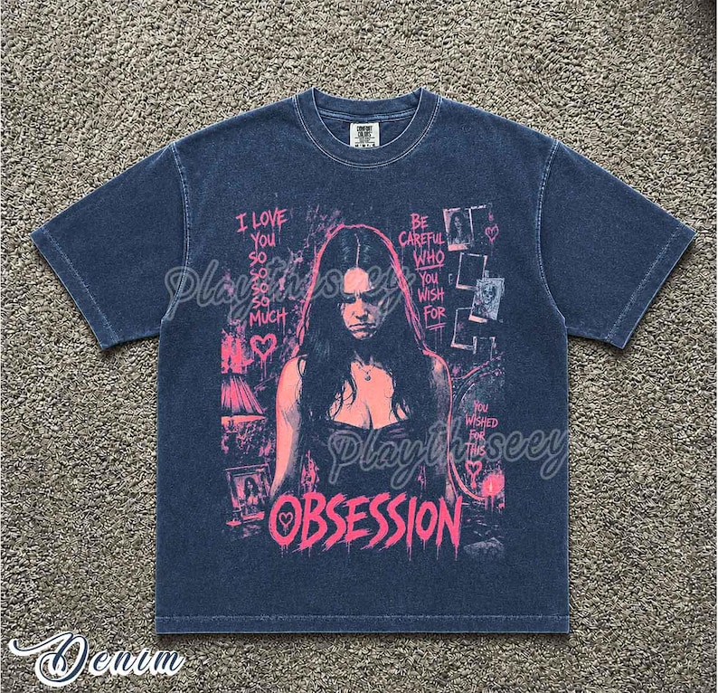 May include: A dark blue short-sleeve t-shirt featuring a pink graphic print of a person with long hair. The text reads I LOVE YOU SO SO SO SO MUCH, BE CAREFUL WHO YOU WISH FOR, YOU WISHED FOR THIS, and OBSESSION, along with heart icons.