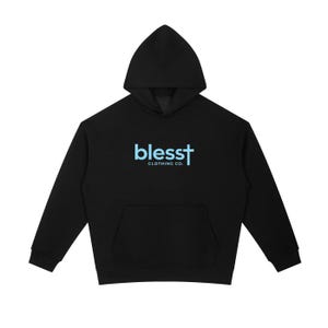 May include: A black long-sleeve hooded sweatshirt featuring a front kangaroo pocket. The center of the chest displays the light blue text "blesst" with a cross replacing the letter "t", followed by the white text "CLOTHING CO." underneath.