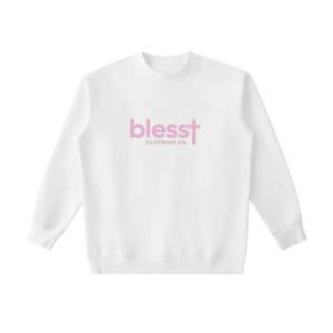 May include: A white long-sleeve crewneck sweatshirt featuring the text "blesst" in light pink, with the letter "t" stylized as a cross, and the words "CLOTHING CO." printed in smaller light pink capital letters directly underneath the main logo.