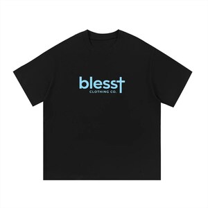May include: A black short-sleeved t-shirt featuring the light blue text "blesst" with a cross integrated into the final letter, followed by the words "CLOTHING CO." in smaller light blue capital letters centered on the chest area.