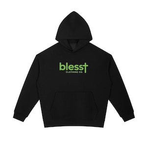 May include: A black long-sleeve hooded sweatshirt featuring a front kangaroo pocket and a lime green graphic on the chest that reads "blesst" with a cross replacing the letter "t", followed by the text "CLOTHING CO." in smaller lime green letters.
