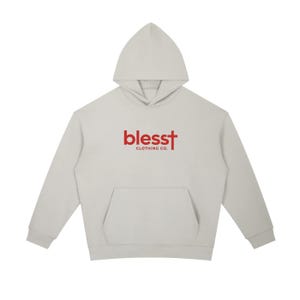 May include: A light gray hooded sweatshirt featuring long sleeves, a front kangaroo pocket, and the red text "blesst CLOTHING CO." printed on the chest, where the letter "t" is stylized as a cross.