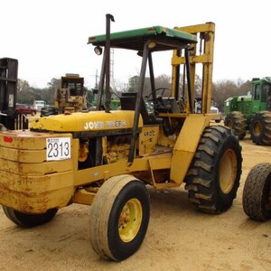 Op de afbeelding: Een gele John Deere 480C vorkheftruck met een groen dak, grote zwarte banden en een wit rechthoekig bord aan de voorzijde met de zwarte tekst 2313. Het robuuste industriële voertuig heeft een verticale mast en een open bestuurderscabine.