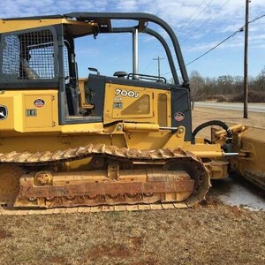 Puede incluir: Una topadora sobre orugas John Deere 700J LGP de color amarillo con una jaula protectora negra, orugas metálicas y una gran hoja frontal. La maquinaria de construcción pesada muestra el logotipo de John Deere y el modelo en los paneles.