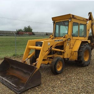 Puede incluir: Una retroexcavadora amarilla John Deere con una pala frontal y un brazo excavador trasero. El vehículo de construcción pesado cuenta con una cabina de operador cerrada con ventanas de cristal, neumáticos negros grandes y estructura metálica.