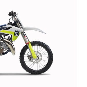 May include: A Husqvarna TC 85 motorcycle repair manual cover featuring the text REPARATURANLEITUNG 2021, TC 85, and Art.-Nr. 3403128de. The image displays the front section of a white, yellow, and blue motocross bike with a black knobby tyre.