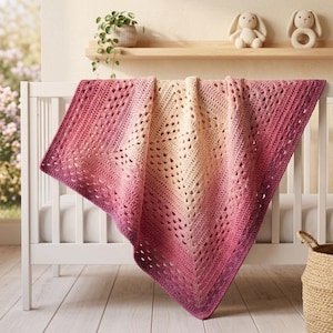 May include: A square crochet blanket featuring an ombre color gradient that transitions from a light cream center to deep magenta and purple edges. The blanket has a textured, open-work stitch pattern and is draped over a white wooden crib railing.