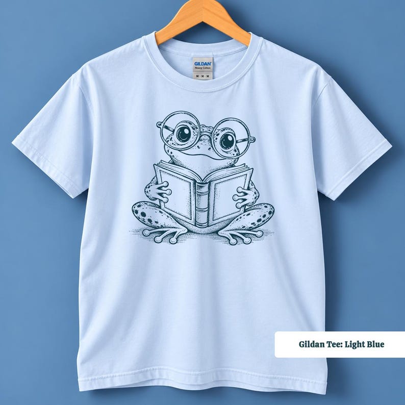 Book lover shirt with an adorable hand sketched frog in big round glasses enjoying an open book, cute frog shirt, book club sweatshirt, reading shirt, frog reading shirt, bookish shirt, book club shirt, library shirt, book lover gift, frog lover gift, frog sweatshirt, bookish sweatshirt, comfort colors shirt, reader shirt, bookworm gift, reading lover gift, librarian gift, book club gift, cute frog shirt for readers, frog gift