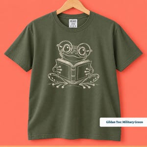 Cute frog shirt showing a quirky hand drawn frog wearing big nerdy round glasses while reading a book, book club sweatshirt, book lover shirt, reading shirt, frog reading shirt, bookish shirt, book club shirt, library shirt, book lover gift, frog lover gift, frog sweatshirt, bookish sweatshirt, comfort colors shirt, cute bookworm shirt, reader gift, librarian gift, book club gift, reading lover gift, frog reader shirt