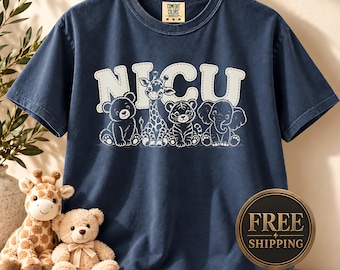 May include: A navy blue short-sleeve t-shirt featuring the white text NICU above a graphic of a bear, giraffe, tiger, and elephant. The shirt has a Comfort Colors brand label at the inner neckline and is displayed on a wooden hanger.