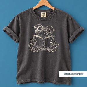 Book lover shirt featuring a cute hand drawn frog reading a book in oversized nerdy glasses, cute frog shirt, book club sweatshirt, reading shirt, frog reading shirt, bookish shirt, book club shirt, library shirt, book lover gift, frog lover gift, frog sweatshirt, bookish sweatshirt, comfort colors shirt, bookworm shirt, reader gift, reading lover shirt, librarian gift, cute book shirt, frog gift, book club gift