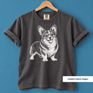 A corgi shirt and corgi merchandise design featuring a lovable corgi with glasses and a quirky vintage aesthetic. The artwork gives this corgi glasses shirt a retro corgi shirt feel while appealing to fans of geeky corgi shirts, nerdy dog shirts, and vintage dog tees.