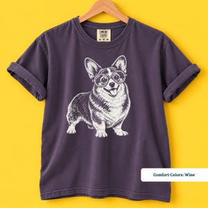 This corgi shirt and corgi merchandise mockup shows a charming corgi with glasses in a fun retro inspired design. A great example of a geeky corgi shirt, corgi nerd shirt, and vintage corgi shirt that also makes a playful nerdy dog shirt for corgi lovers.