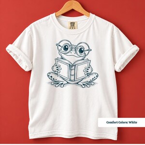 Book lover gift featuring a cute sketch frog wearing large round glasses while reading a book, cute frog shirt, book club sweatshirt, book lover shirt, reading shirt, frog reading shirt, bookish shirt, book club shirt, library shirt, frog lover gift, frog sweatshirt, bookish sweatshirt, comfort colors shirt, bookworm gift, reader gift, reading lover gift, librarian gift, cute frog gift, book club gift, bookish reader shirt