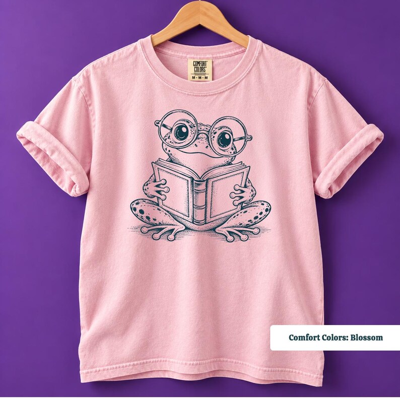 Cute frog shirt for book lovers featuring a whimsical hand sketched frog reading an open book with oversized round glasses, book club sweatshirt, book lover shirt, reading shirt, frog reading shirt, bookish shirt, book club shirt, library shirt, book lover gift, frog lover gift, frog sweatshirt, bookish sweatshirt, comfort colors shirt, bookworm shirt, reader gift, librarian gift, book club gift, reading gift, frog lover shirt