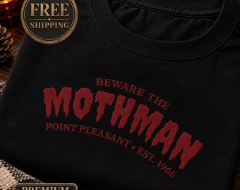 May include: A black crewneck sweatshirt featuring red embroidered text that reads BEWARE THE MOTHMAN, POINT PLEASANT, and EST. 1966. The word MOTHMAN is displayed in a large, textured, distressed font across the center of the chest.