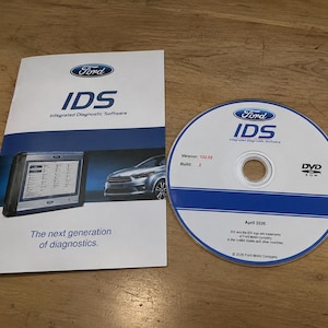 Könnte beinhalten: Ein Ford IDS Integrated Diagnostic Software Handbuch und eine zugehörige DVD-ROM. Das Handbuch zeigt das Ford-Logo, ein Bild eines Diagnosetablets, ein Auto und den Text 'The next generation of diagnostics.' Die Disc zeigt die Version 132.02.