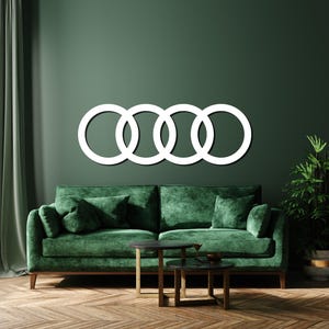 May include: A white wall-mounted sign featuring four interlocking circles arranged in a horizontal row. The design consists of four identical circular rings connected to each other, creating a continuous chain-like pattern against the wall.