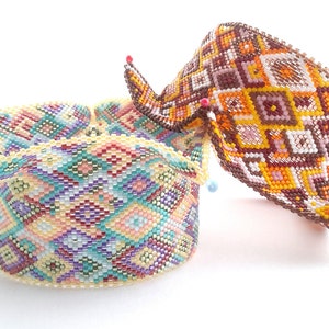 May include: Two colorful beaded baskets with geometric patterns. The baskets are made of small beads in shades of brown, yellow, orange, pink, blue, and white. The baskets are folded into a bowl shape.