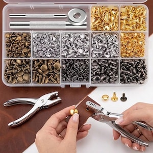 May include: A clear plastic storage container filled with assorted metal rivets in gold, silver, bronze, and gunmetal finishes, alongside two metal setting tools. Below, a silver hole punch tool is used on a piece of brown leather.