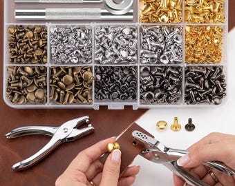 May include: A clear plastic storage container filled with assorted metal rivets in gold, silver, bronze, and gunmetal finishes, alongside two metal setting tools. Below, a silver hole punch tool is used on a piece of brown leather.