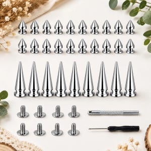 May include: A collection of silver-colored metal spikes and studs in various lengths, featuring a pointed conical shape. The set includes threaded screw-back fasteners, a small metal tool with a textured grip, and a black-handled precision screwdriver.
