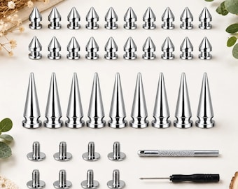 May include: A collection of silver-colored metal spikes and studs in various lengths, featuring a pointed conical shape. The set includes threaded screw-back fasteners, a small metal tool with a textured grip, and a black-handled precision screwdriver.